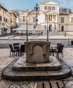 pozzo, piazza, sedie, tavolini, finestre, ombrelloni, cielo, tombino, case, gradini, persone, gazebo, porte, azzurro, alberi, bar, chiesa, palazzo, palazzi, tavoli, arco